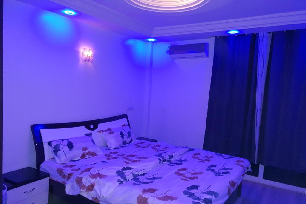 Schlafzimmer mit einem Bett mit violetter Bettwäsche und blauen Lichtern in der Unterkunft Luxueux Appartement F3 in Dakar