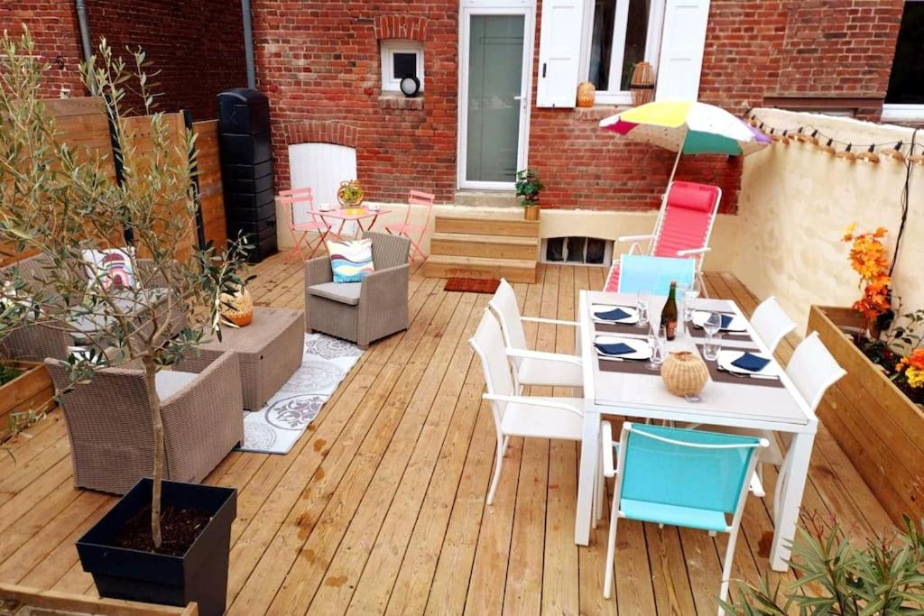 une terrasse avec une table, des chaises et un parasol dans l'établissement Maison de vacances familiale à Trouville-sur-mer, à Trouville-sur-Mer