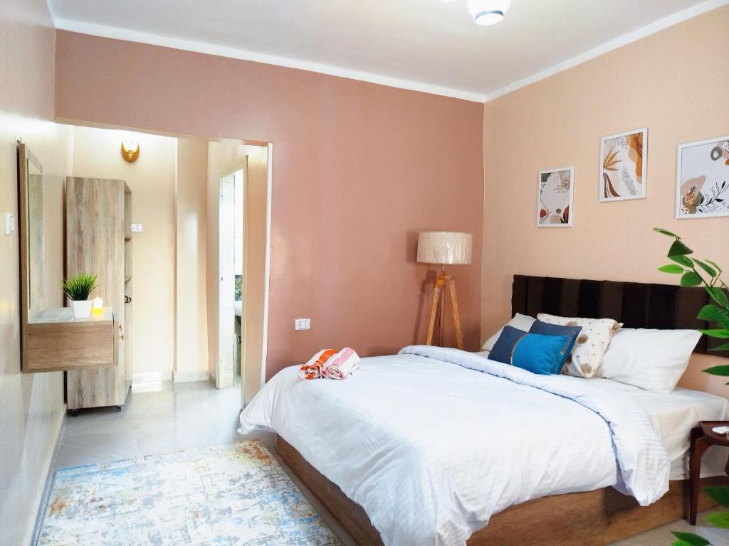 a bedroom with a large bed in a room with pink walls at Moon Homes in Cairo
