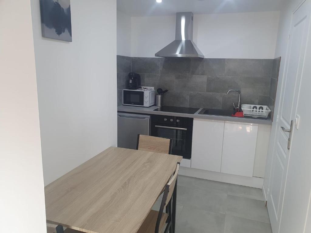 une cuisine avec une table en bois et un micro-ondes dans l'établissement Maison plain pied avec jardin, à Villeneuve-le-Roi