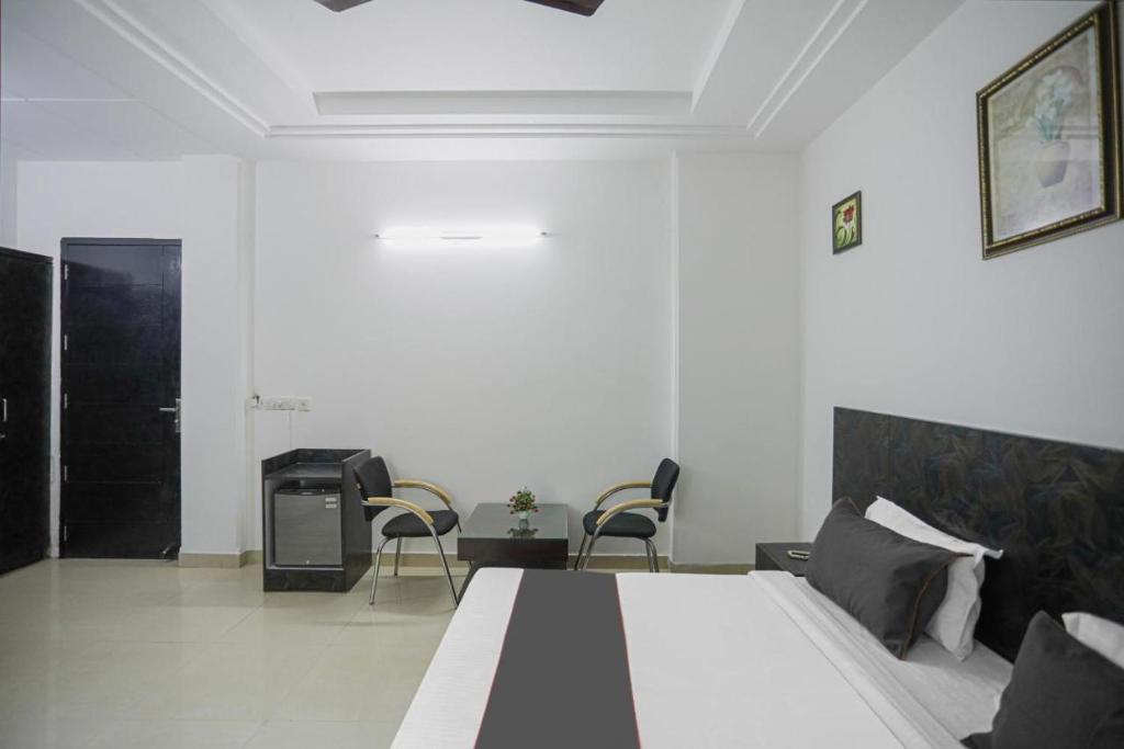 sypialnia z dużym łóżkiem i 2 krzesłami w obiekcie StayKar by Loomstay w mieście Gurgaon