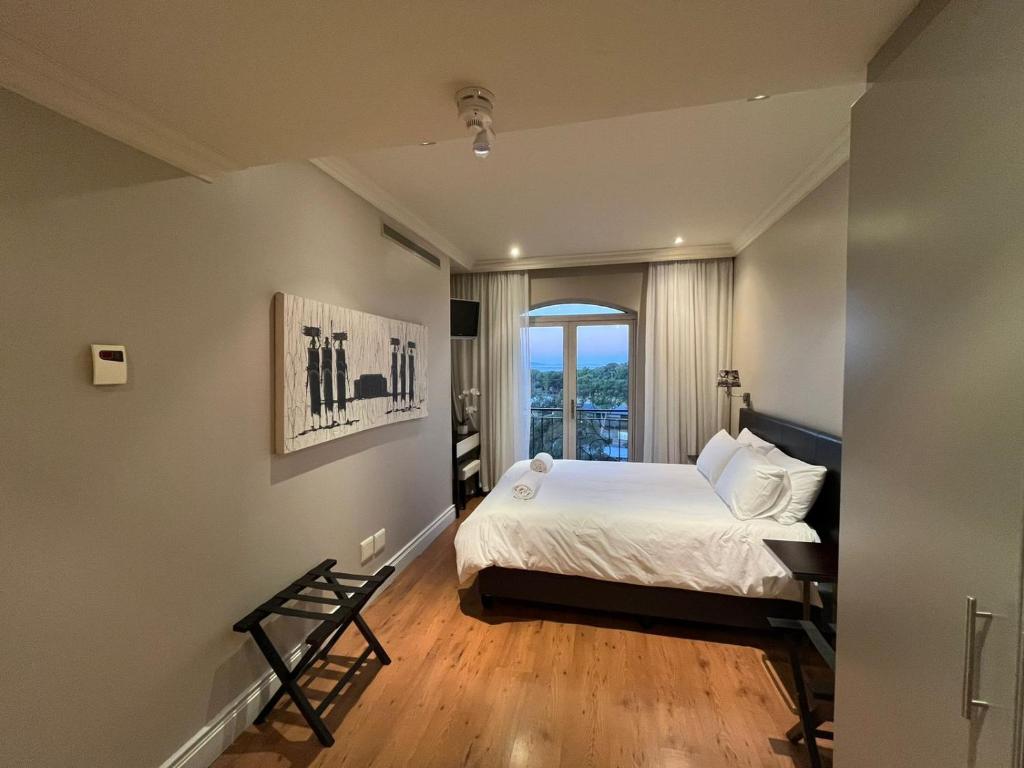 1 dormitorio con cama, ventana y escritorio en Cape Royale Luxury Suite, en Ciudad del Cabo