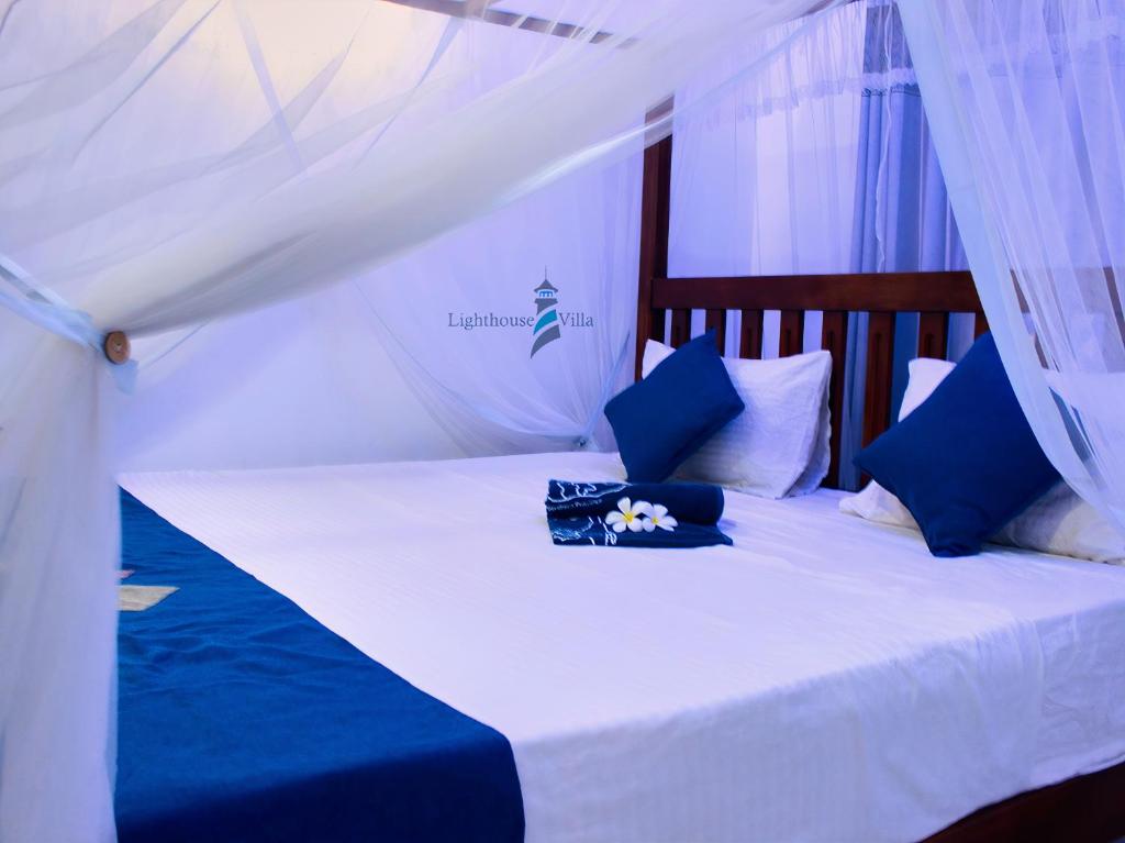 a bed with blue and white pillows and a canopy at Lighthouse Villa Koggala in Galle