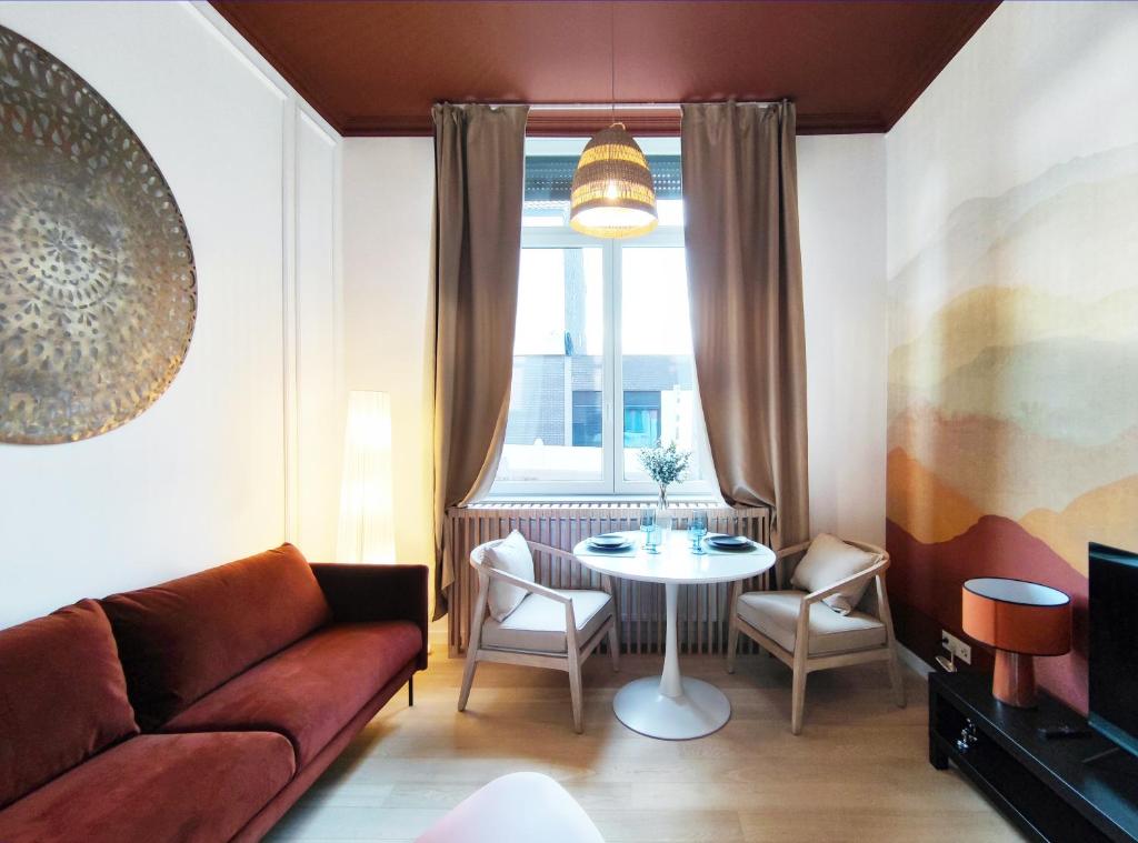 ein Wohnzimmer mit einem Sofa, einem Tisch und einem Fenster in der Unterkunft L'appart by Authentic in Saint-Ghislain