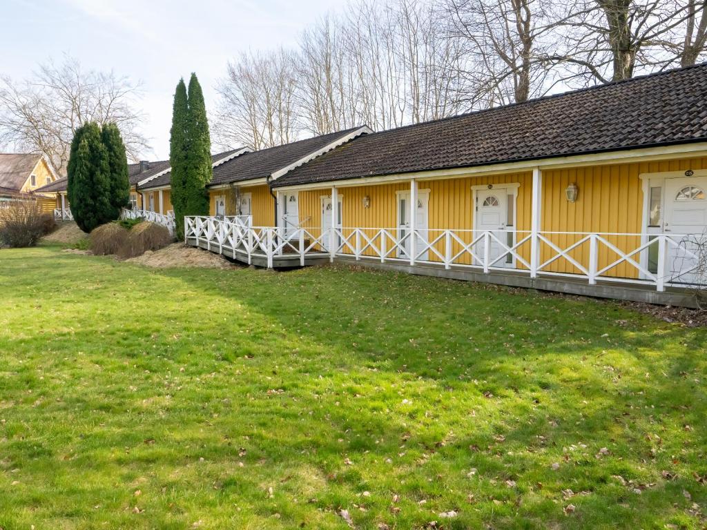 a yellow house with a lawn in front of it at Spångens Gästgivaregård in Ljungbyhed