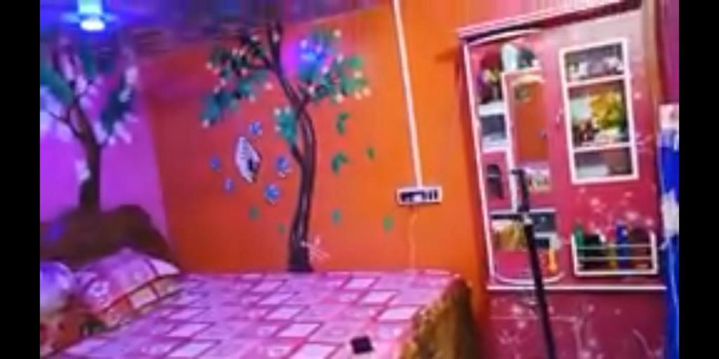 a bedroom with a tree painted on the wall at Hours home in Kolkata