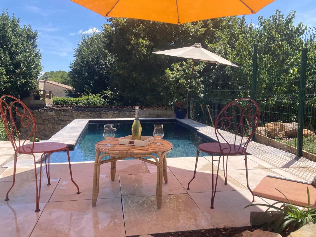 - une table avec des verres à vin et un parasol à côté de la piscine dans l'établissement La Villa Tranquille aux portes des Cévennes, à Brissac