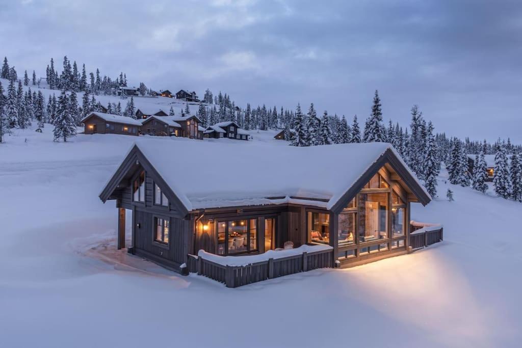 a house in the snow with lights on at Hyttekos Lodge: luxury ski-in/ski-out chalet in Kvitfjell