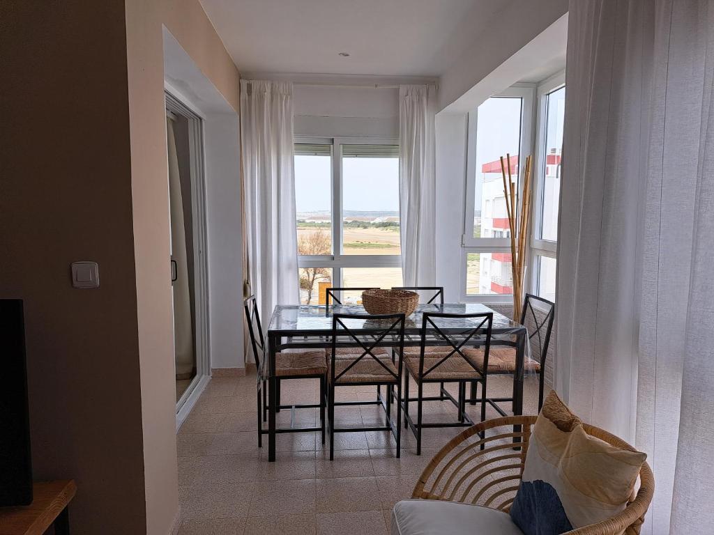 jadalnia ze stołem i krzesłami oraz oknem w obiekcie Ático primera línea de playa con vistas al mar-Climatizado-Wifi-Parking w mieście El Puerto de Santa María