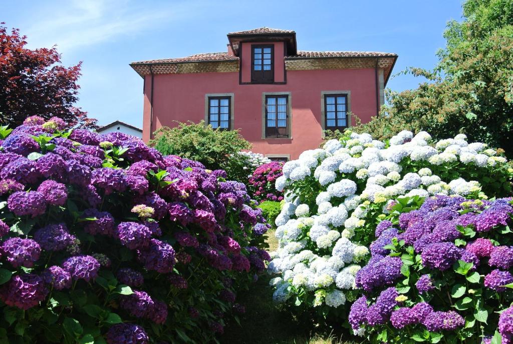 un jardín de flores púrpuras y blancas frente a una casa en Hotel Rural El Algaire, en Arquera de Sales