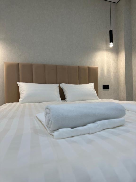 uma grande cama branca com lençóis e almofadas brancos em 1 комнатная квартира посуточно em Taldykolʼ