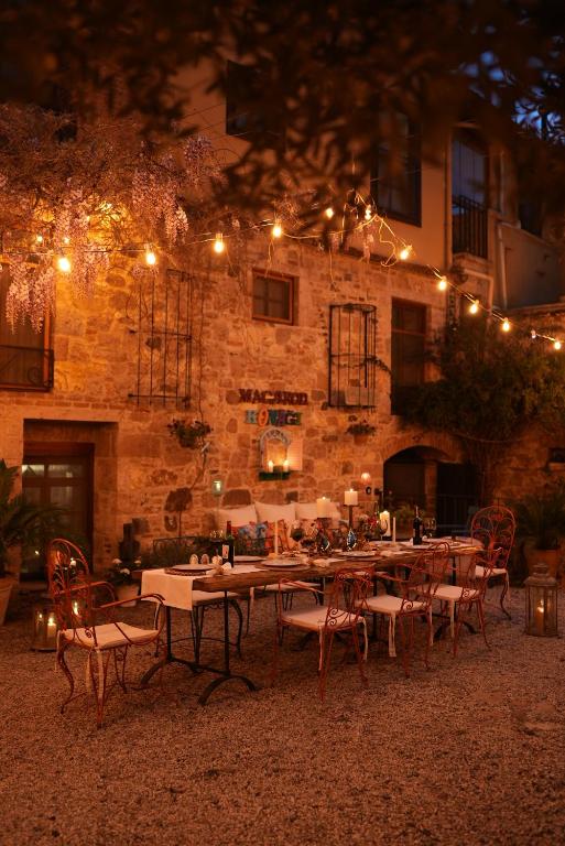 a table and chairs in front of a building with lights at Macaron Konagi in Ayvalık