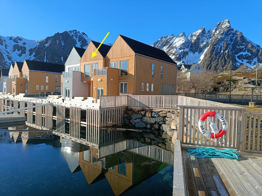 a building on the water with mountains in the background at Superior Ocean View Lofoten in Ballstad