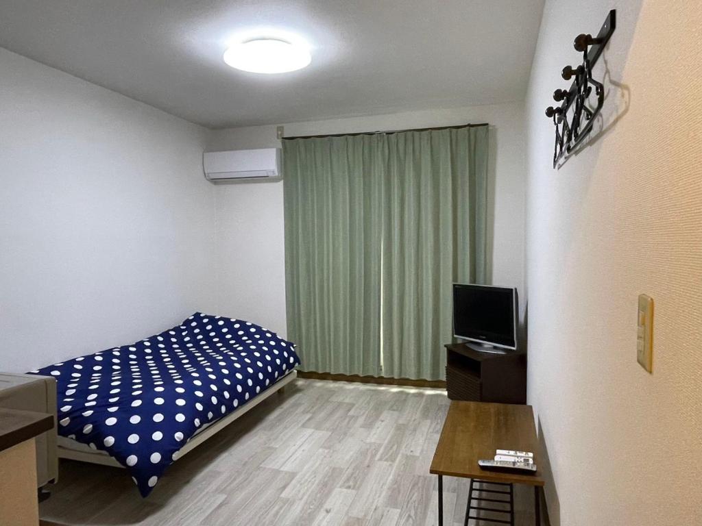 ein kleines Zimmer mit einem Bett und einem Fernseher in der Unterkunft アルピエe207号室 軽自動車のみ敷地内無料駐車場Wi-Fi付き in Kumamoto