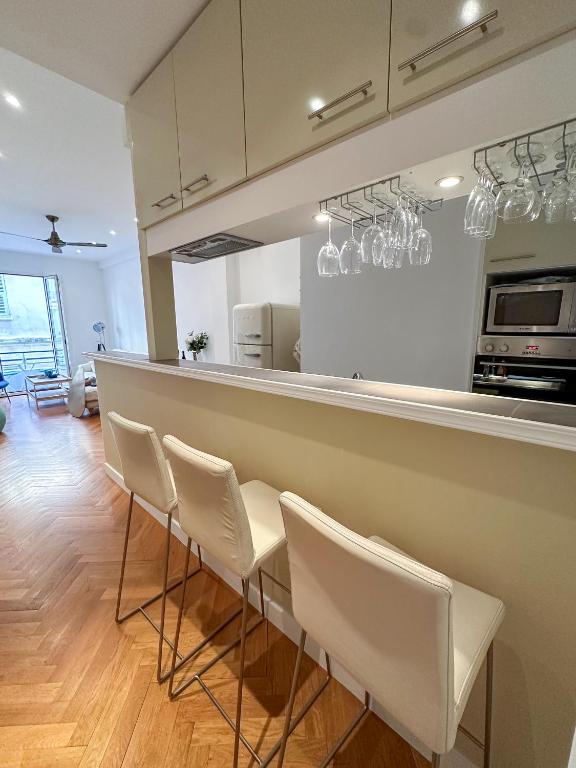 une cuisine avec un bar et des chaises blanches dans l'établissement Les Terrasses D'Herold, à Nice