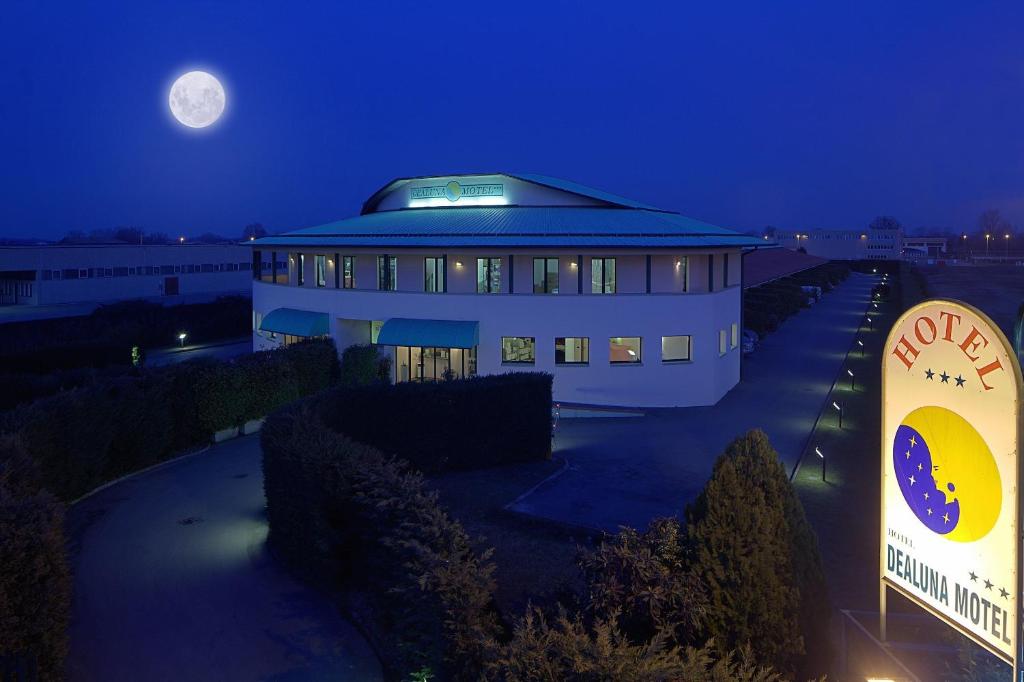 een groot gebouw 's nachts met een maan in de lucht bij Dealuna Motel in Fidenza