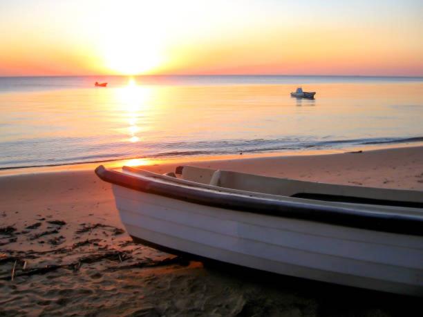 a boat sitting on the beach at sunset at Katembe Beach Paradise in Maputo