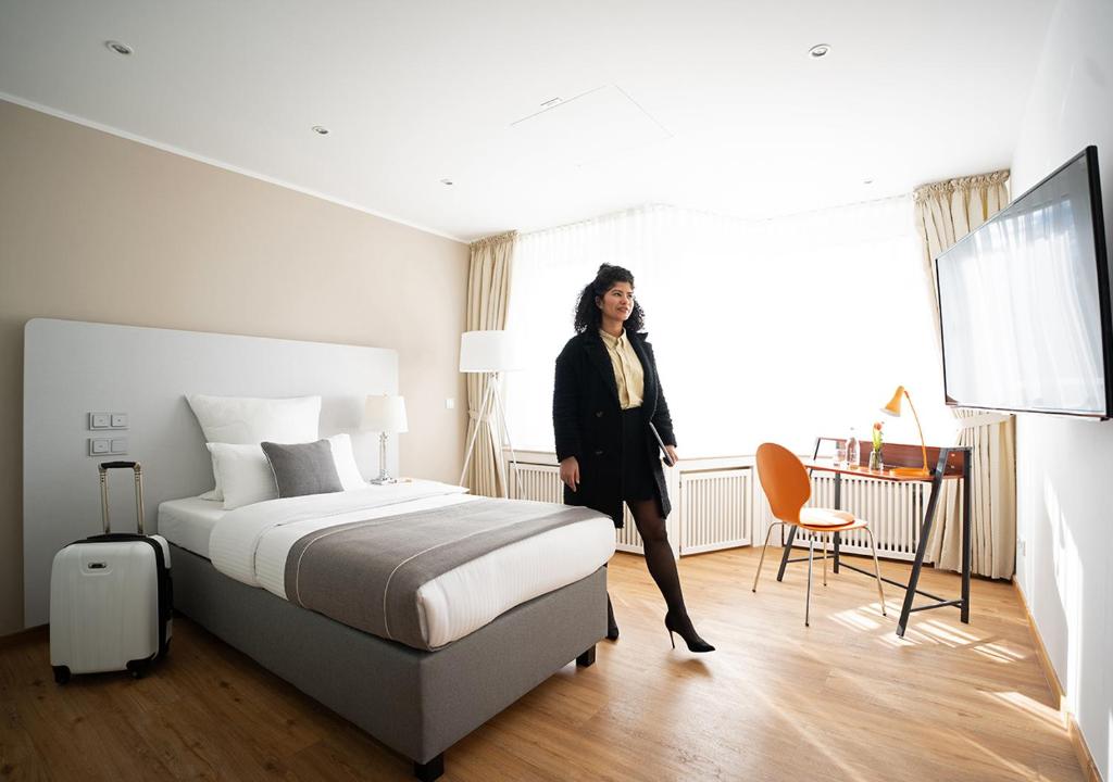 a woman standing next to a bed in a hotel room at Hotel Am Brinkerplatz in Essen