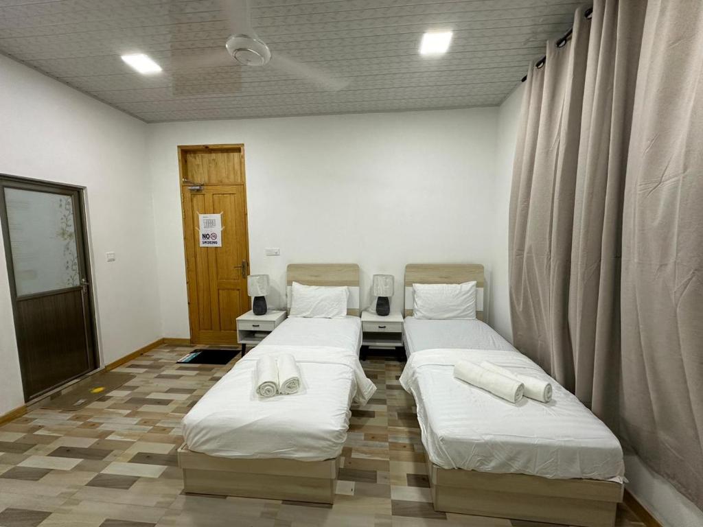 een kamer met 2 bedden en handdoeken erop bij The Happiness Sun Suites in Fodhdhoo