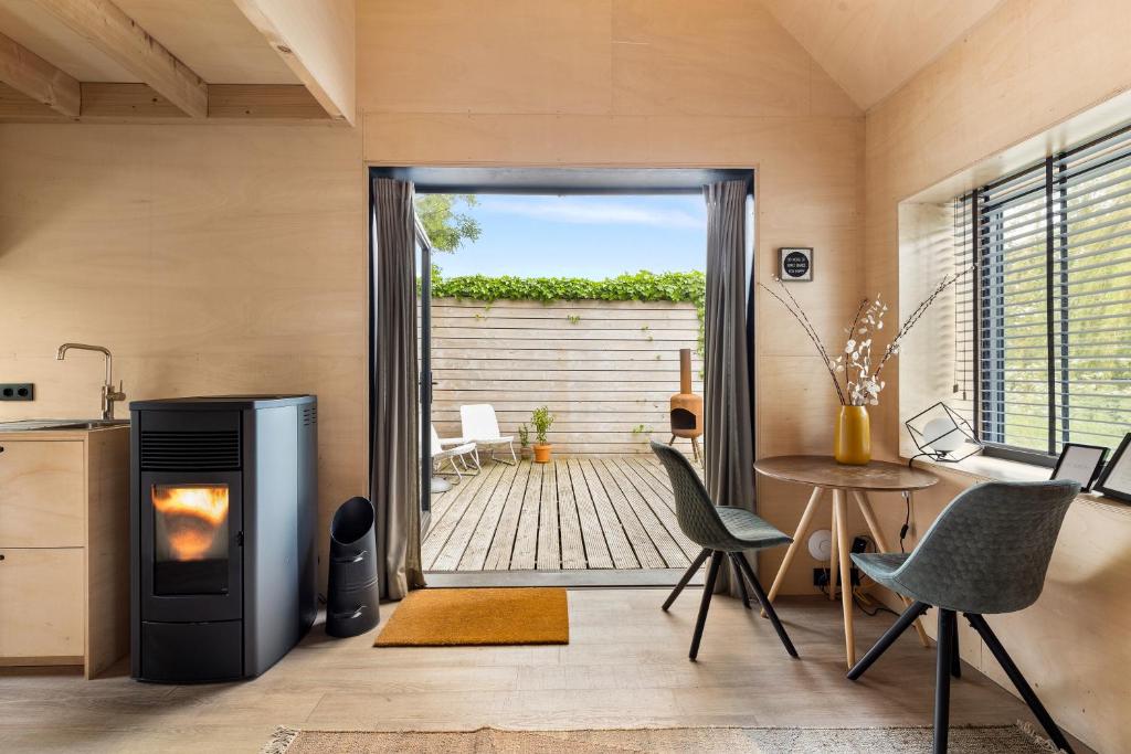 een woonkamer met een open haard en een tafel en stoelen bij Hello Zeeland - Tiny Houses Groede in Groede