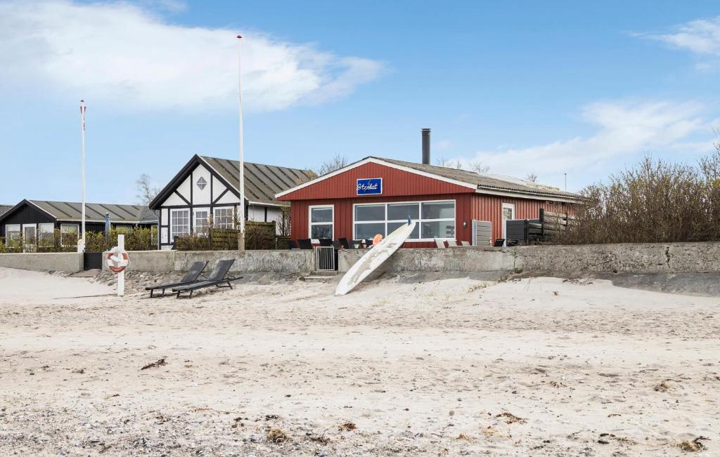 2 Bedroom Beach Front Home In Otterup في Otterup: جلسة على لوح التزلج في الرمال أمام المبنى