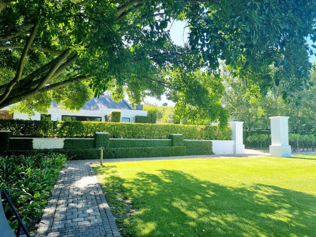 einen Garten mit einem Haus im Hintergrund in der Unterkunft Brenaissance Wine & Stud Estate in Stellenbosch