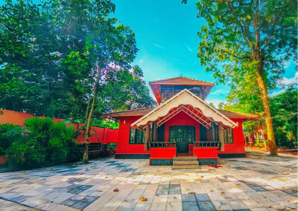 un edificio rojo con sillas rojas en un patio en The Stream View Villas Wayanad, en Vythiri