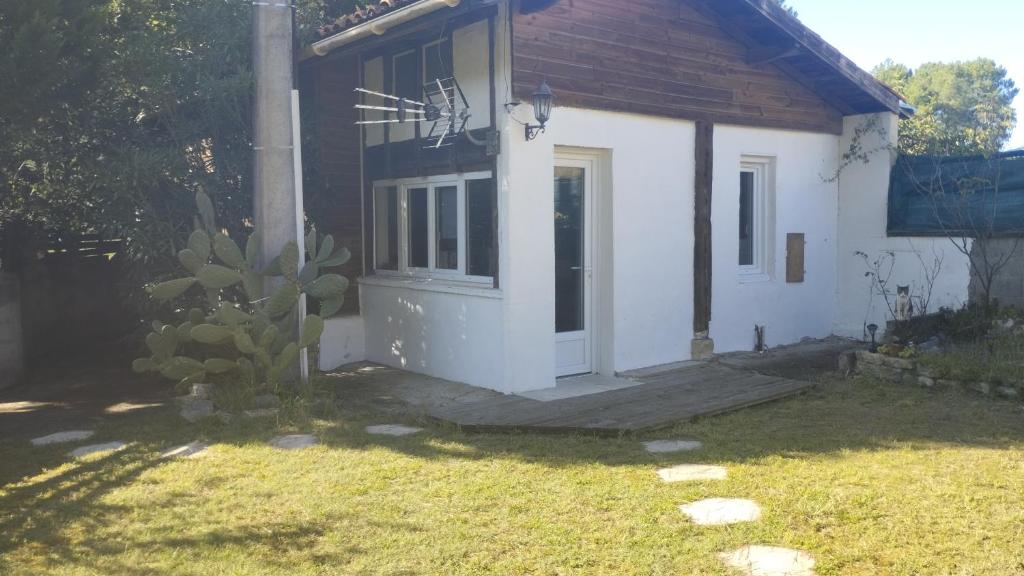 une petite maison blanche avec une porte dans une cour dans l'établissement Maison proche de l'océan, à Labenne