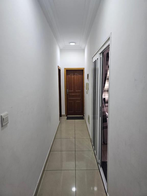 a hallway with white walls and a wooden door at Appartement de luxe in Cotonou