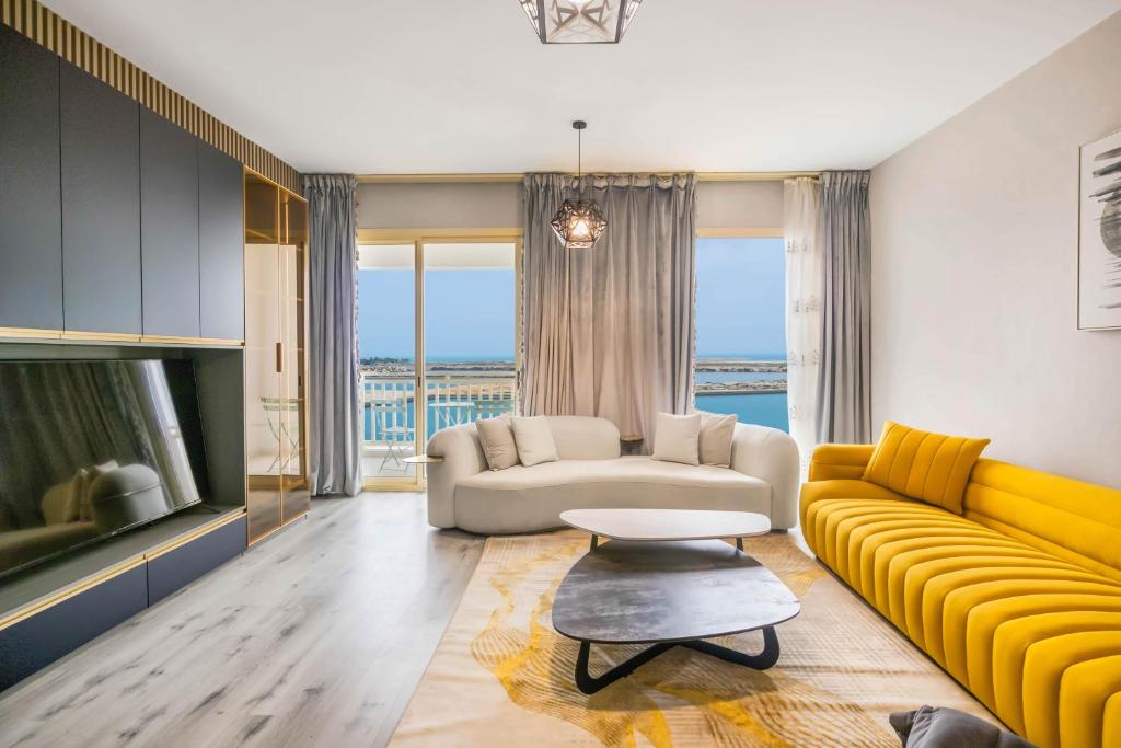 un soggiorno con divano giallo e TV di Water surrounded beautiful 2BR apartment a Ras al Khaimah