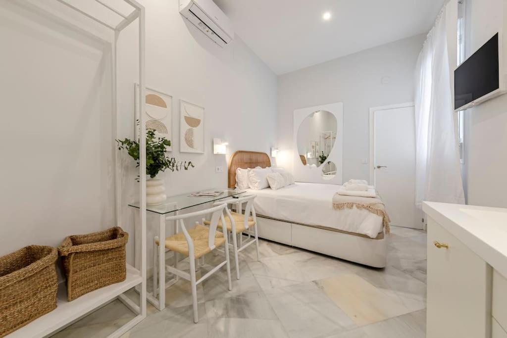 um quarto branco com uma cama e uma mesa em Indulge Group: Downtown Cuna 1.0 em Sevilha