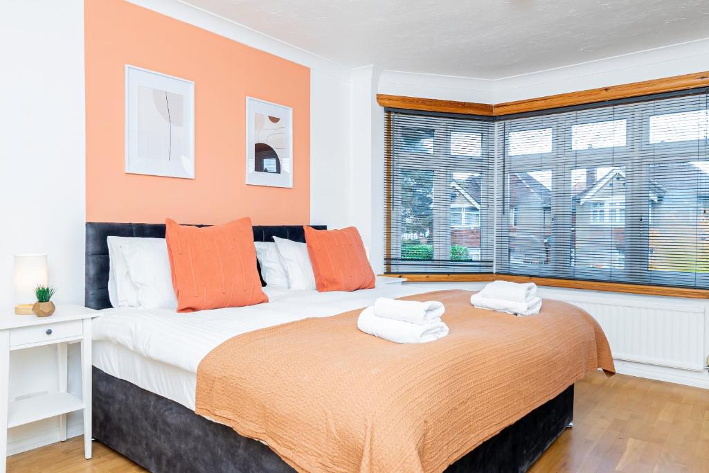 una camera da letto con un grande letto con cuscini arancioni di 4-bed Retreat, Spacious Oasis With Modern Comfort a Southampton