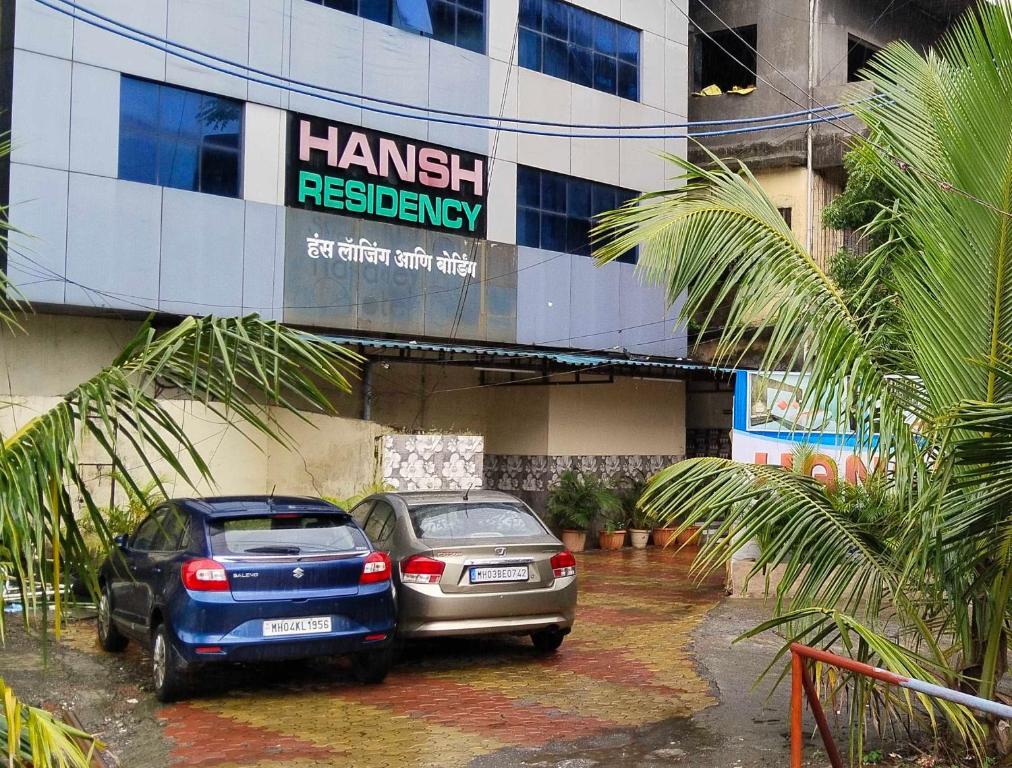dos autos estacionados en un estacionamiento frente a un edificio en Hansh Residency, en Bombay