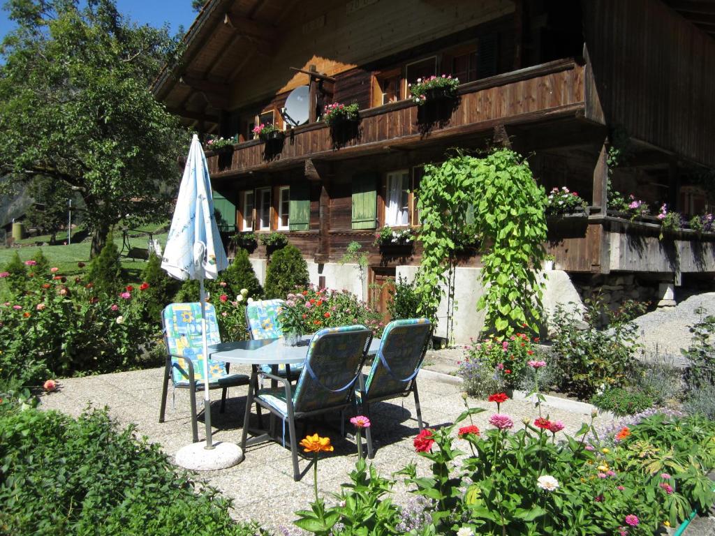 uma mesa e cadeiras num jardim em frente a um edifício em Apartment Lindi em Lütschental