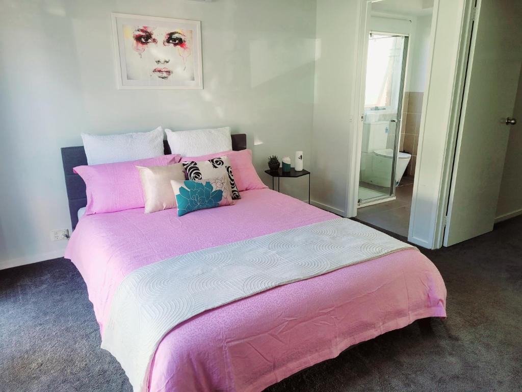 una camera con letto rosa e bianco con cuscini di Home away from home a Melton