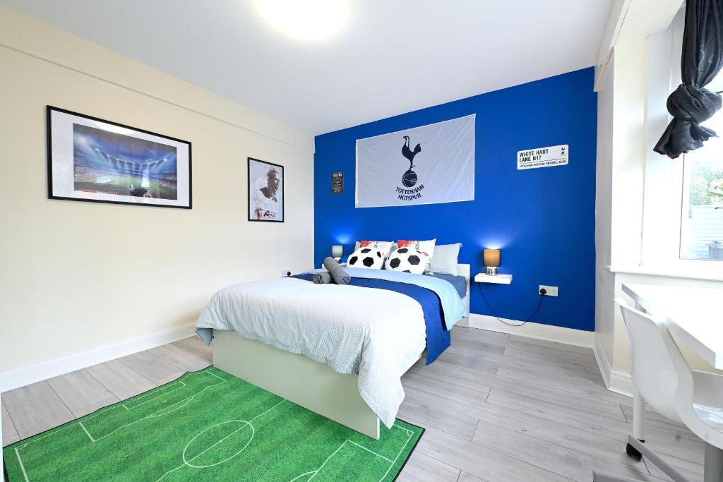 SPACIOUS 5 BEDROOM HOUSE NEXT TO TOTTENHAM STADIUM في لندن: غرفة نوم بجدران زرقاء وسرير مع الوسائد