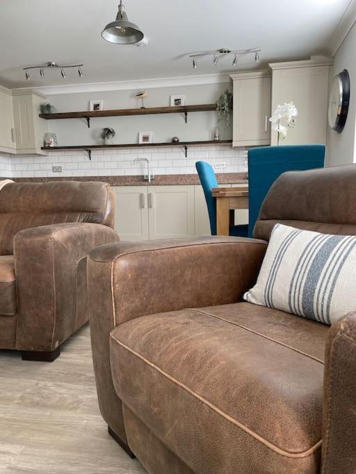 a living room with two couches and a kitchen at Seaside Modern Apartment in Westward Ho