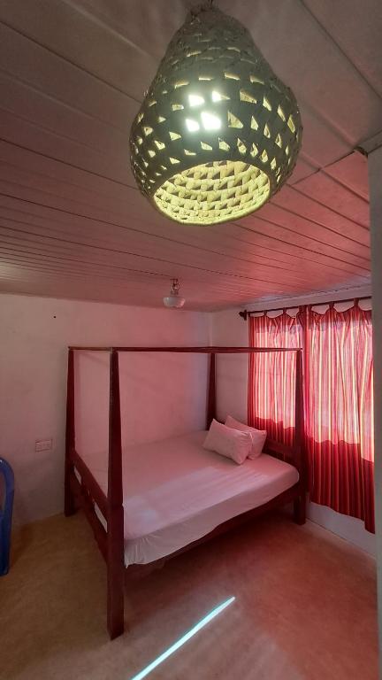 a small bed in a room with a large chandelier at Roof Top Private House in Lamu