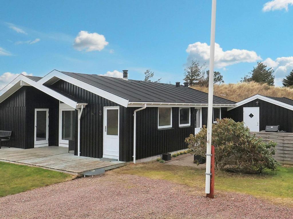 een zwart-wit huis met een veranda bij Holiday home Blokhus LXVI in Blokhus