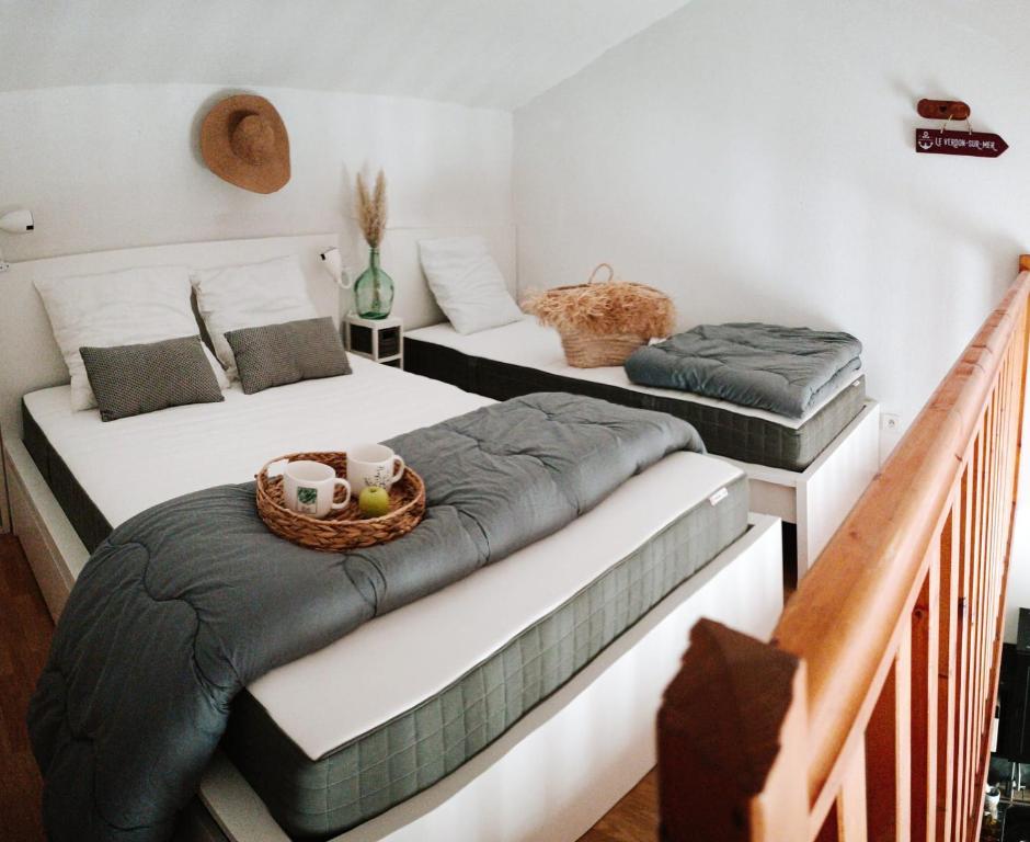 two twin beds in a bedroom with a basket at Au Cordouan in Le Verdon-sur-Mer