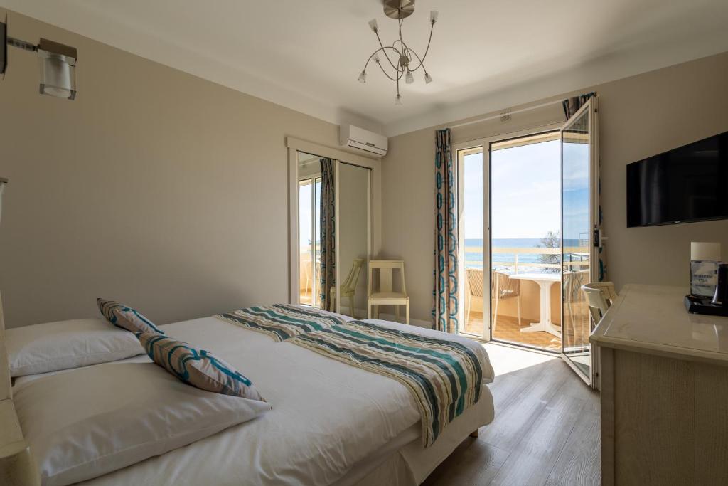 a bedroom with a bed with a view of the ocean at Hôtel Méditerranée in Le Lavandou