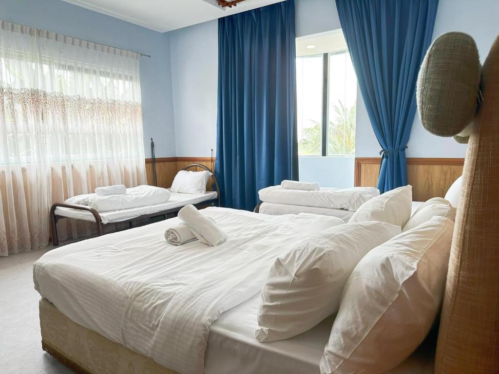 Duas camas num quarto com paredes e janelas azuis em Spacious BBQ Gathering Masai Megaria em Masai