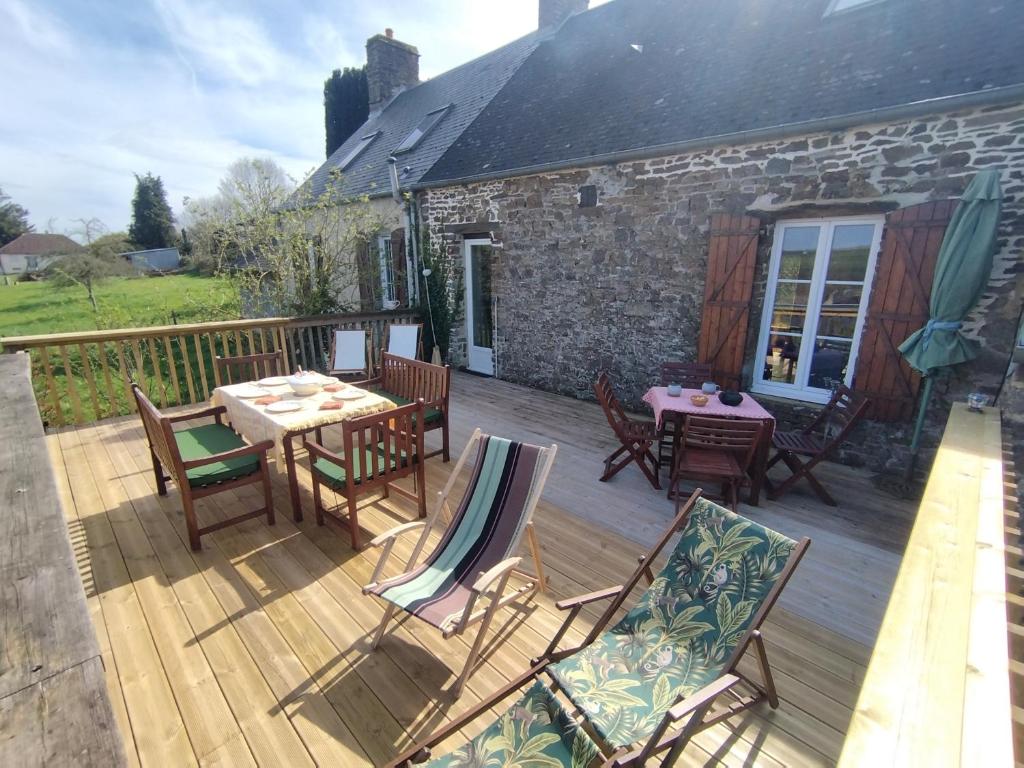 une terrasse en bois avec des tables et des chaises sur une maison dans l'établissement Chalet des Roches Roche d'Oëtre Suisse Normande, à Saint-Philbert-sur-Orne