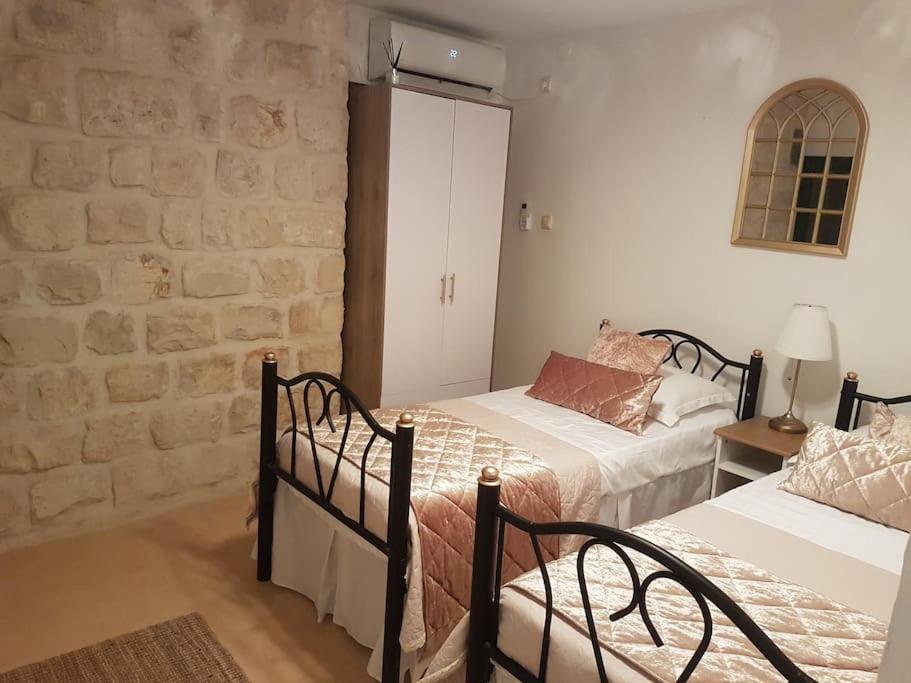 1 dormitorio con 2 camas y pared de piedra en Two stand-alone flats on the cliff with wild animals, Galilee Sea & Mountains View en Safed