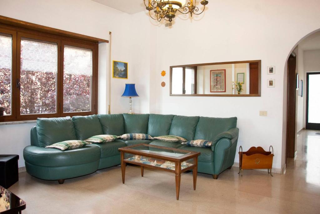 un soggiorno con divano verde e tavolo di Centra House - Big Gardened Flat Near Rome a Velletri