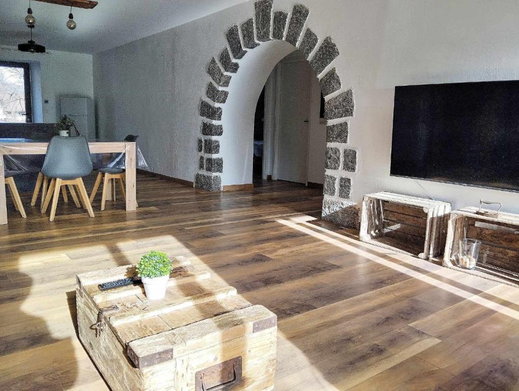 una sala de estar con un arco con TV y mesa en LE MAZOT-SPA HIVER ET ETE-Piscine-Proche lac-Charme-Détente, en Lathuile