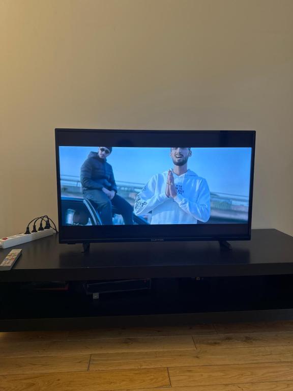 a flat screen tv sitting on a black table at Stationnement Gratuit, 3mn du Métro, Parfait pour Télétravailler in Maisons-Alfort