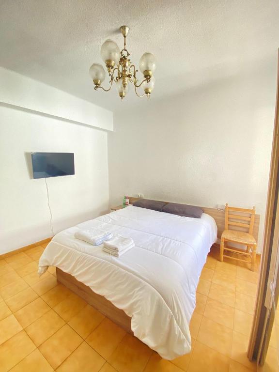 Un dormitorio con una gran cama blanca y una lámpara de araña. en Habitacion Vacacional en piso compartido, en Castellón de la Plana