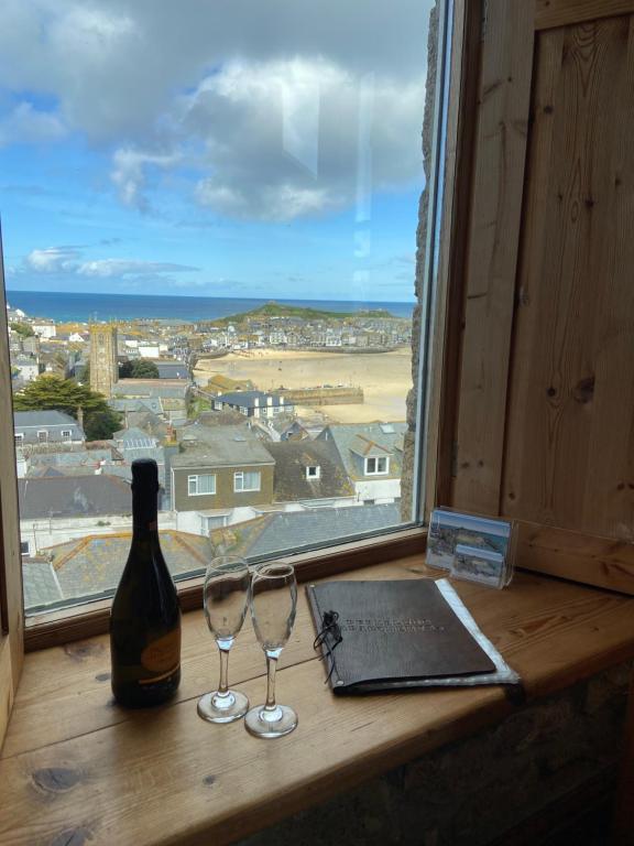 una ventana con una botella de vino y dos copas de vino en HUER'S WATCH a beautifully presented PRIVATE APARTMENT with far reaching VIEWS Over ST IVES HARBOUR and BAY and FREE ONSITE PARKING for LARGER GROUPS book along with our Connecting TWO SISTER APARTMENTS, en St Ives