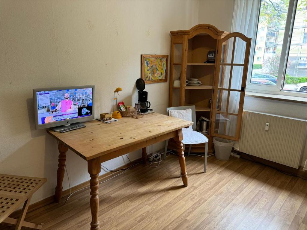 a room with a wooden table with a television on it at Gemütliches komfortables Zimmer für 1 Person im Zentrum in Munich